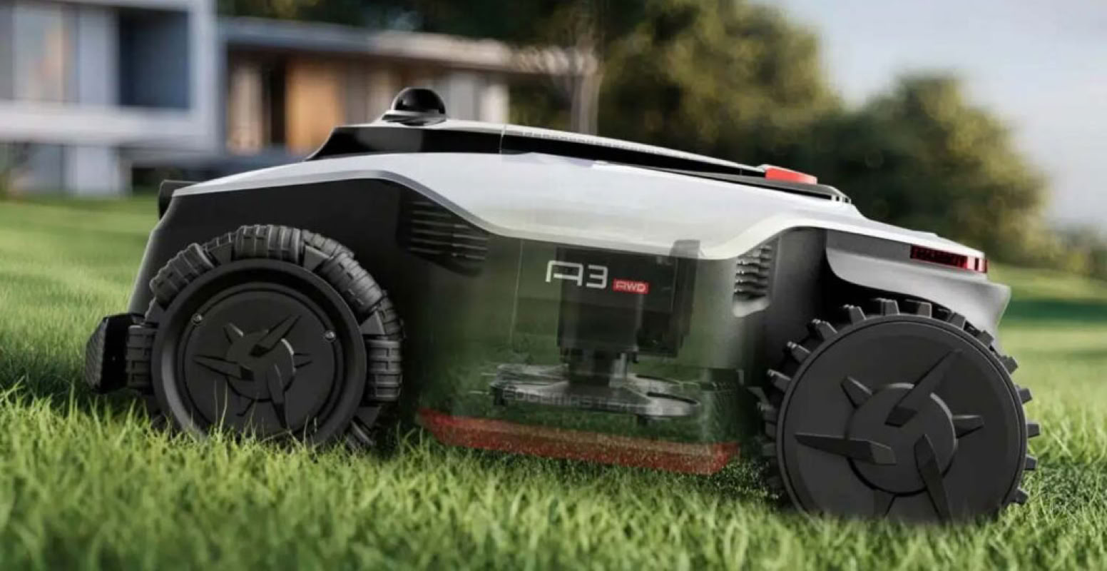 Une tondeuse robotique Dreame sur une pelouse verte avec une maison floue en arrière-plan.