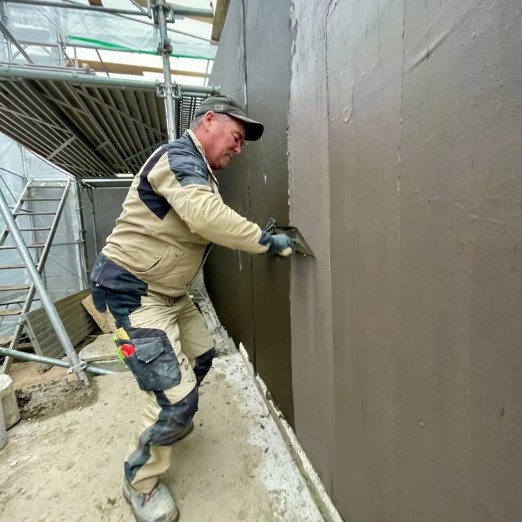 Rond-point à Meinier avec des arbres et des fleurs au centre, entouré d'une route, ciel partiellement nuageux.